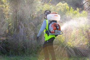 A man spraying product to control midges outside