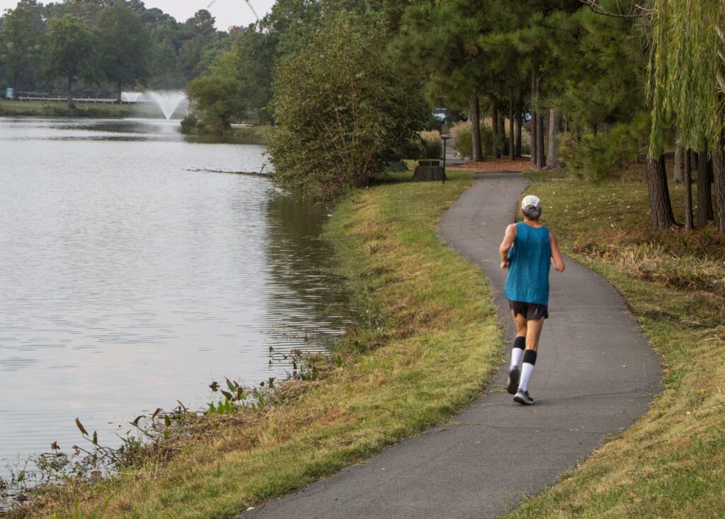 A man jogging along a residential lake